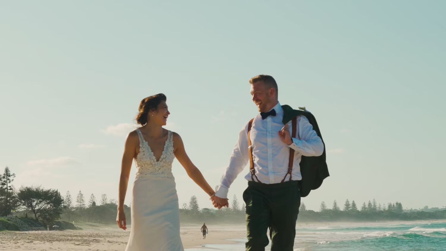 Bride and groom walking hand in hand along a beach